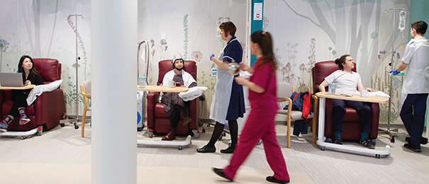 Three chairs in the Chemotherapy Suite against a wall with a floral mural and surrounded by curtains for privacy