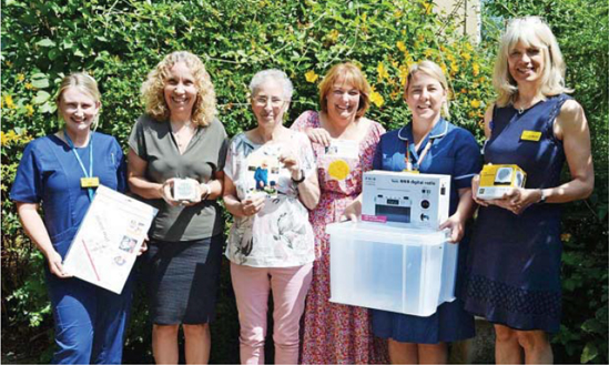 Bob Brown's daughters and wafe alongside RUH staff. One is holding a Bob's Box, the other is holding a radio.