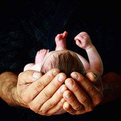 Baby being held in the palms of a man's hands