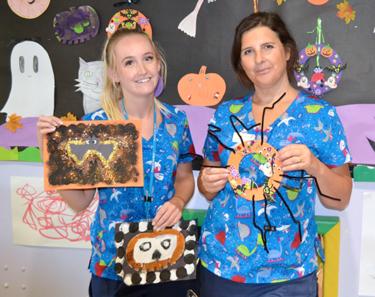 Edwina Bridgeman and Charlotte Stowell holding up children's artworks