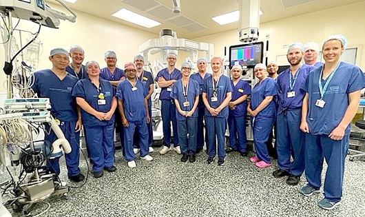 A group of surgeons posing with the Da Vinci surgical robot