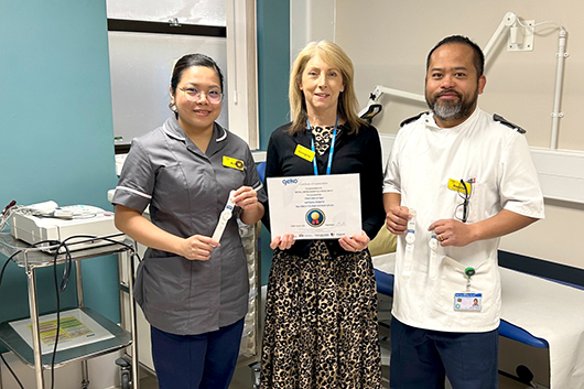 RUH staff holding up the geko device and a certificate