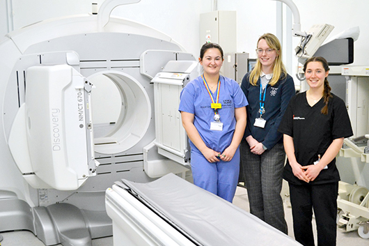 Healthcare scientests standing in front of a CT scanner