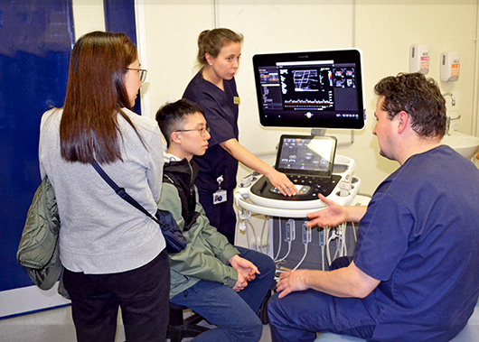 Attendees of the careers fair watching a demonstration of an piece of diagnostic equipment