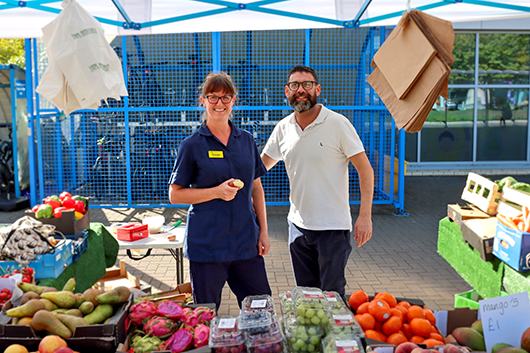 Dean Cooper and Junior Sister Georgie at the fruit and veg stall, surrounded by fresh produce