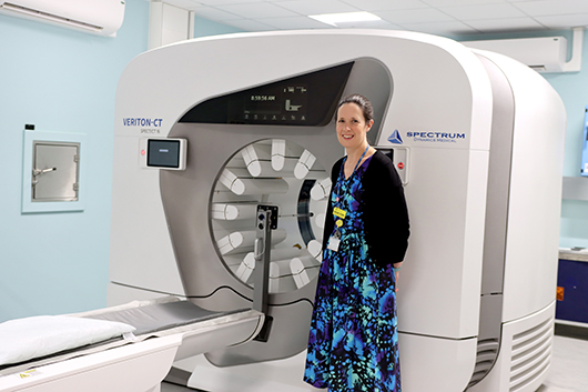 Sarah Cade standing in front of the SPECT-CT scanner